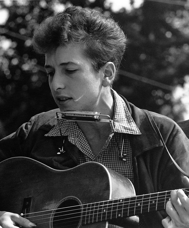 Here, Bob Dylan performs at the Civil Rights March on Washington, D.C. He played protest songs including 'Only A Pawn in their Game' where he called out the brutal, racist, and brainwashing nature of Southern politicians and the inhumanity of those who follow them. (Photo Credit: Rowland Scherman, Public domain, via Wikimedia Commons)